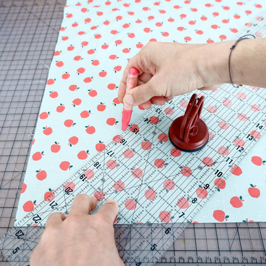 Drawing with a red chalk marker pen on fabric with a print using a ruler with a ruler grip
