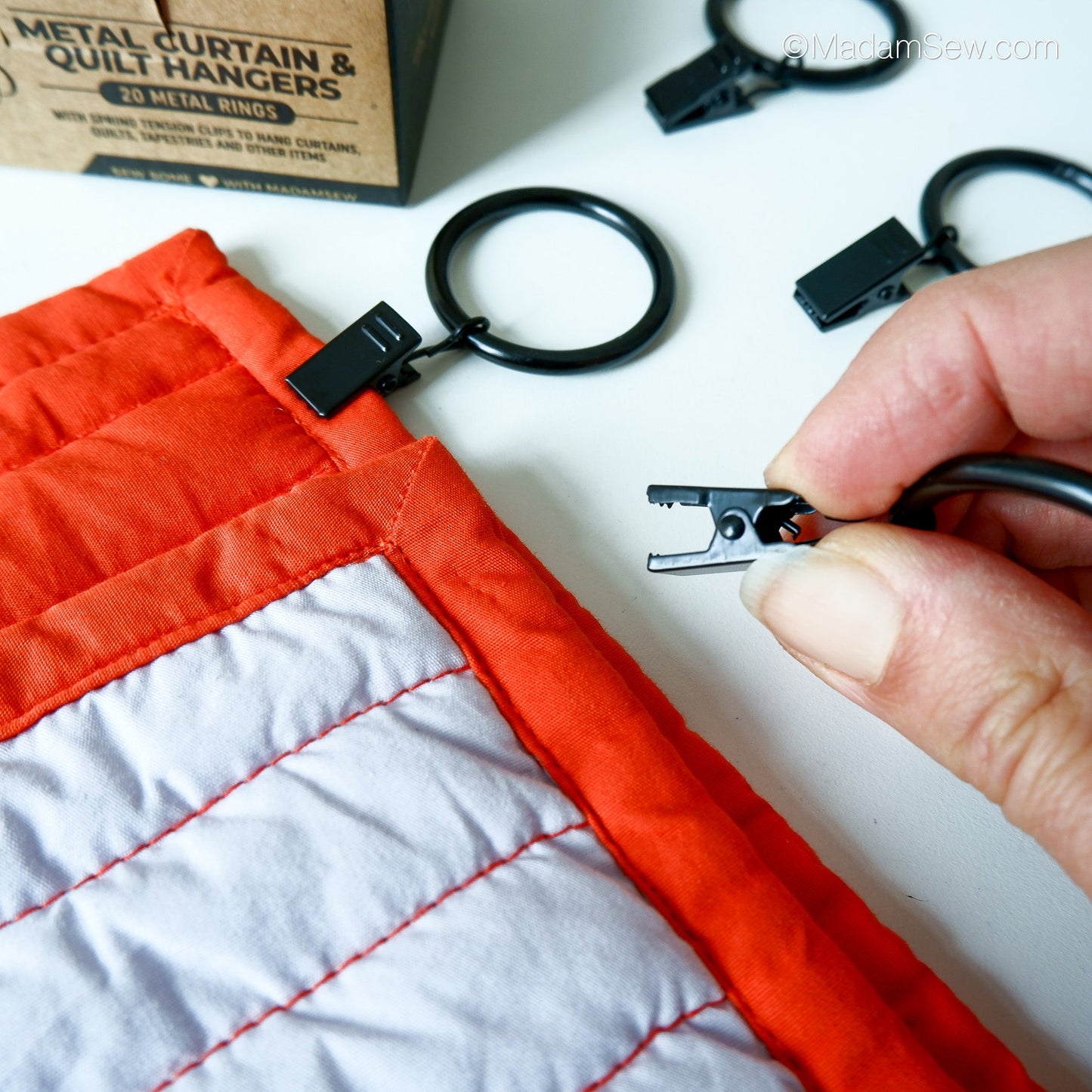 Metal Curtain & Quilt Hanger about to be clipped onto a quilt.
