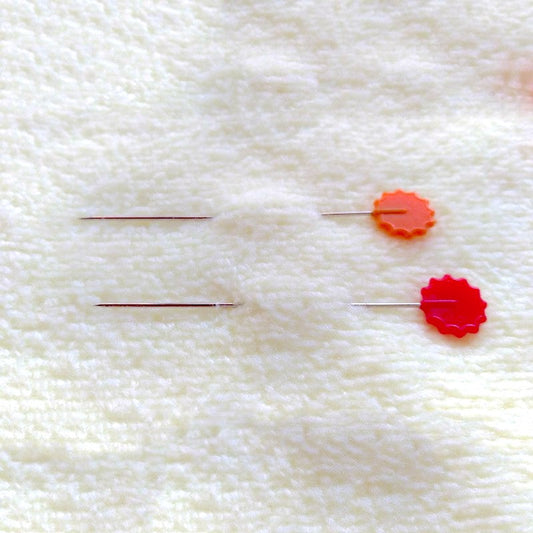 Two long flower pins in batting.